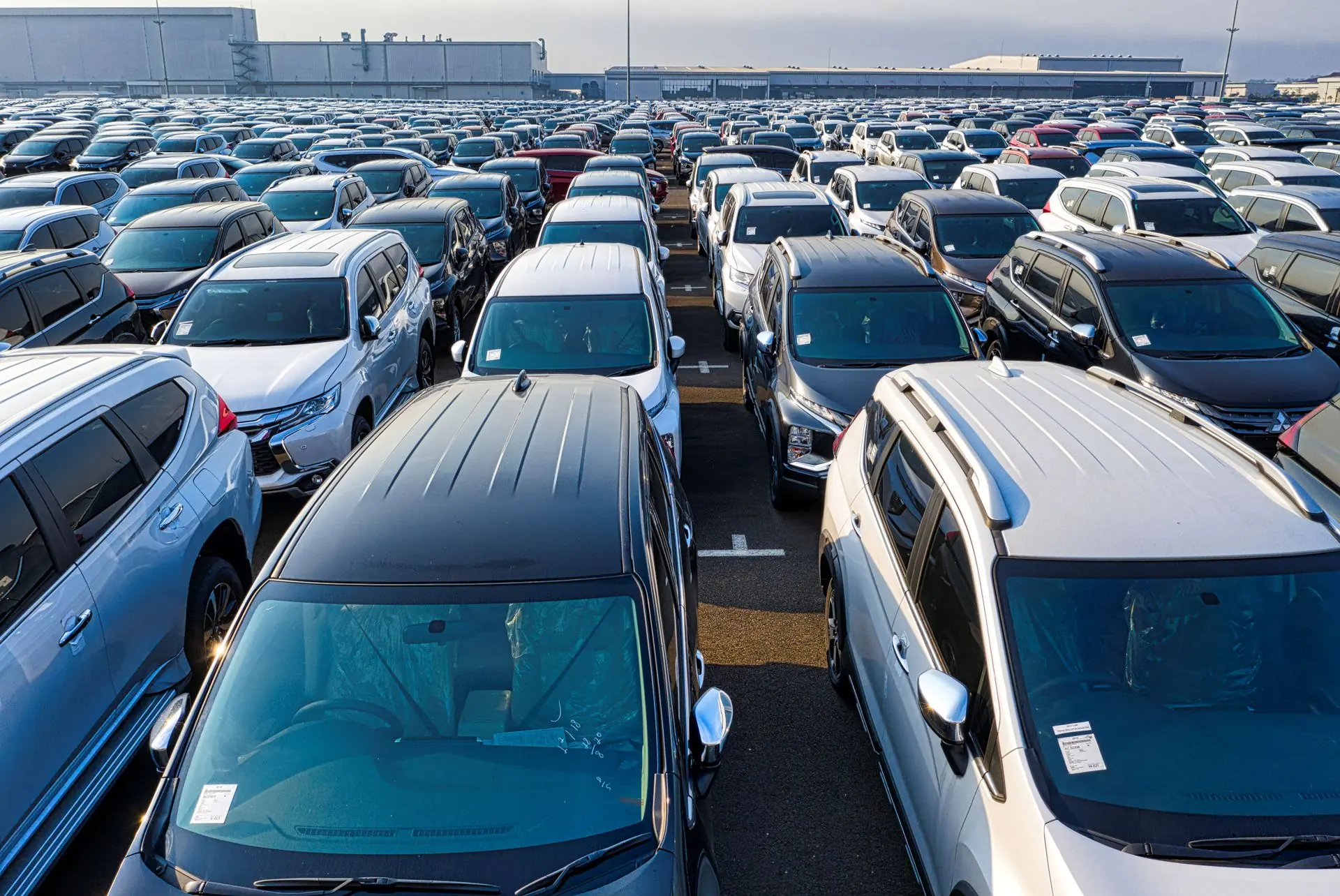 Rows of parked cars in a bright daytime open-air car park